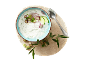 Tzatziki with cucumber, red onion, and spring onion in a bowl, with a spoon and olive branch.