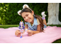 Girl with ear headband lies on a blanket, holding a doll and a unicorn figure.