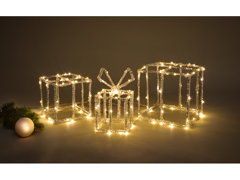 Illuminated Christmas gift boxes and an ornamental bauble with a fir branch.