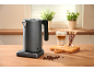 Gray electric kettle with control base, latte coffee, and chocolate sticks on a wooden table.