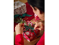 Woman wrapping a Christmas gift in red paper with green ribbon and eucalyptus.