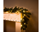 Christmas garland with warm white LED lights draped over a white fireplace.