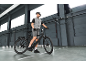 Man in cycling gear on an e-bike in an industrial setting.