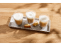 Three glasses of frothy coffee and biscotti on a tray on a wooden table.