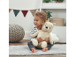 Toddler sitting on rug with a plush bear, looking to the side.