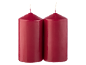 Two red pillar candles with wicks, side by side on a black background.