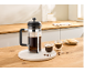 French press with two cups of coffee and cookies on a wooden kitchen counter.