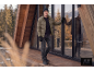 Man in a khaki puffer jacket, black sweater, jeans, and beanie, on a wooden deck.