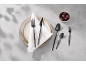 Black cutlery set on a plate with a white napkin and a bowl of olives.