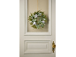 Winter wreath with green foliage, white berries, and pinecones on a door.