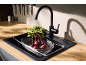 Black kitchen faucet and sink with beetroots in a colander on a wooden countertop.