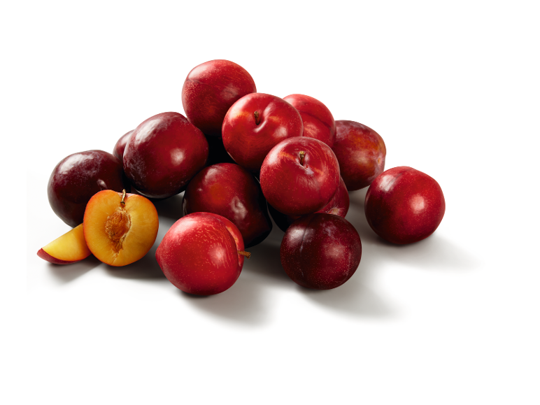 Pile of red plums, with one cut in half revealing the golden flesh.