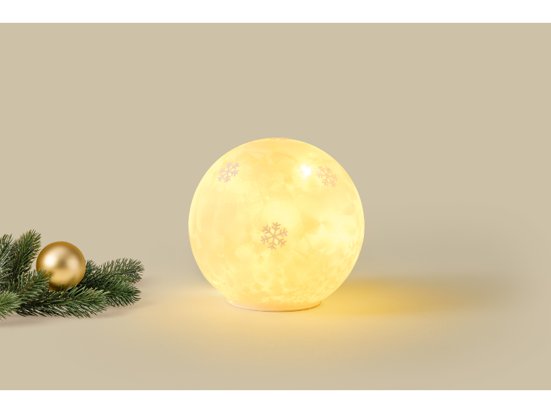 Spherical Christmas light with snowflakes and pine decoration with a golden bauble.