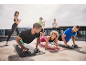 Group of people exercising outdoors with resistance bands, mats, and push-up bars.