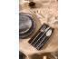 Elegant table setting with dark grey plates, silver cutlery on a napkin, and glassware.