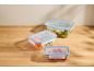 Three glass food storage containers with blue lids, filled with vegetables and salad.