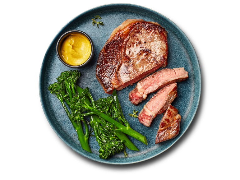 Juicy beef steak served with broccoli and mustard on a blue plate.
