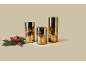 Three gold-colored LED glass cylinders next to a Christmas branch with a red bauble