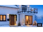 House with Christmas garlands, trees, and light decorations in a snowy landscape.