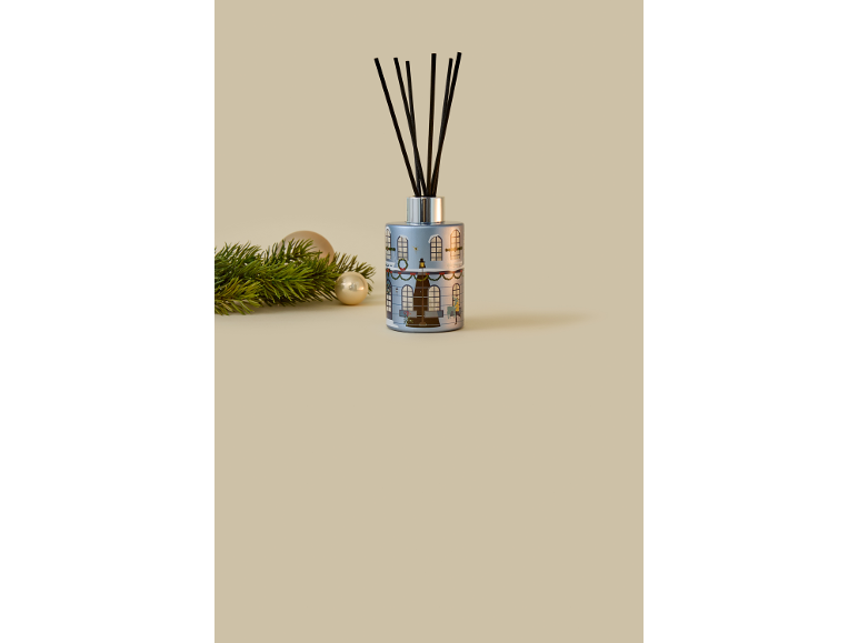 Christmas reed diffuser with black sticks, decorated with a festive house motif.