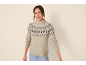 Smiling woman in a knitted sweater with a diamond pattern and jeans.