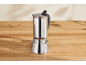Open stainless steel moka pot with coffee on a wooden table