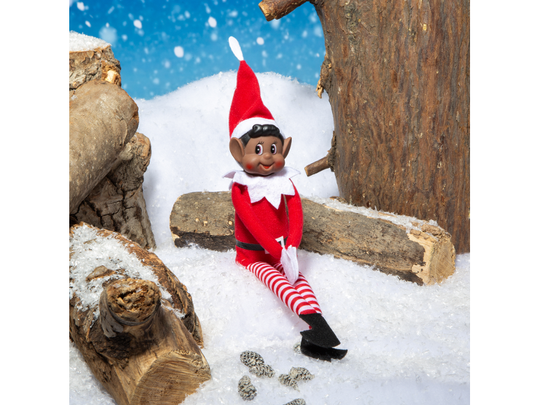 Christmas elf sitting in the snow between wooden logs.