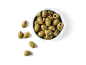 Marinated green olives with garlic and herbs in a white bowl on a black background.