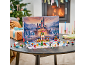 Advent calendar with castle and figures on a table, with a Christmas tree and fireplace in the background.
