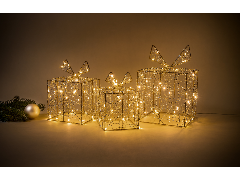 Three glowing Christmas presents with bows and a fir branch with an ornament.