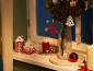 Christmas decoration with candles, a wooden Christmas tree with 'XMAS' text, and bell ornaments.