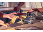 Hands making fresh pasta with a pasta machine on a wooden countertop.