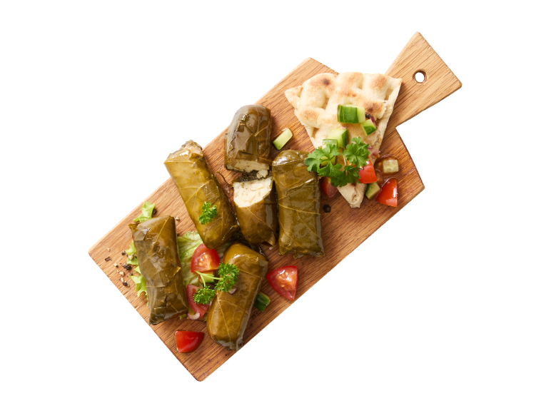 Stuffed vine leaves (dolmades) with fresh salad and flatbread on a wooden board.