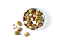 Green olives, feta cheese, and red peppers in a white bowl on a black background.