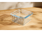 Glass food storage container set on a wooden table with shadows