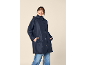 Woman in a dark blue raincoat and jeans, smiling.