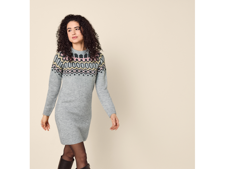 Woman in a knitted dress with a Nordic pattern and black boots.
