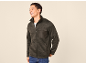 Man in a dark grey fleece jacket with a chest pocket, smiling and looking to the side.