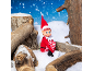 An elf toy sitting among wooden logs in a snowy winter scene.