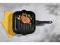 Grilled steak with vegetables in a grill pan, next to a yellow napkin.