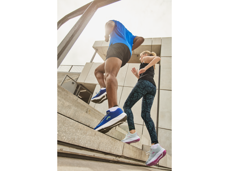 Man and woman in sportswear and sneakers running up stairs.