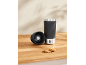 Black thermal mug with a removable lid and two cookies on a wooden surface.