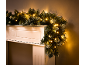 Illuminated Christmas garland with warm lights on a white fireplace.
