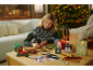 Woman preparing Christmas gift packaging, with a Christmas tree in the background.