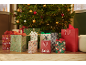 Christmas gift bags and boxes under a Christmas tree with lights and ornaments.