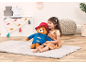 Smiling child hugging a large teddy bear, sitting on a rug in a playful room.