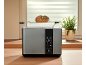 Grey toaster with a digital display and a bun on the warming rack, on a wooden kitchen counter.