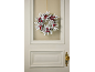 Flocked Christmas wreath with red berries and pinecones on a door.