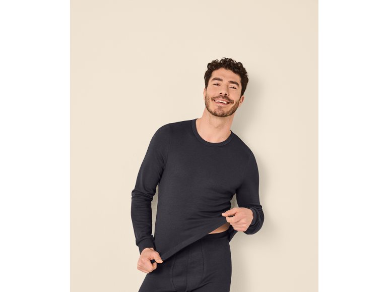 Man in dark blue long-sleeved shirt and underwear.