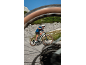Man on an electric bike on a mountain road, shot through a bike wheel.